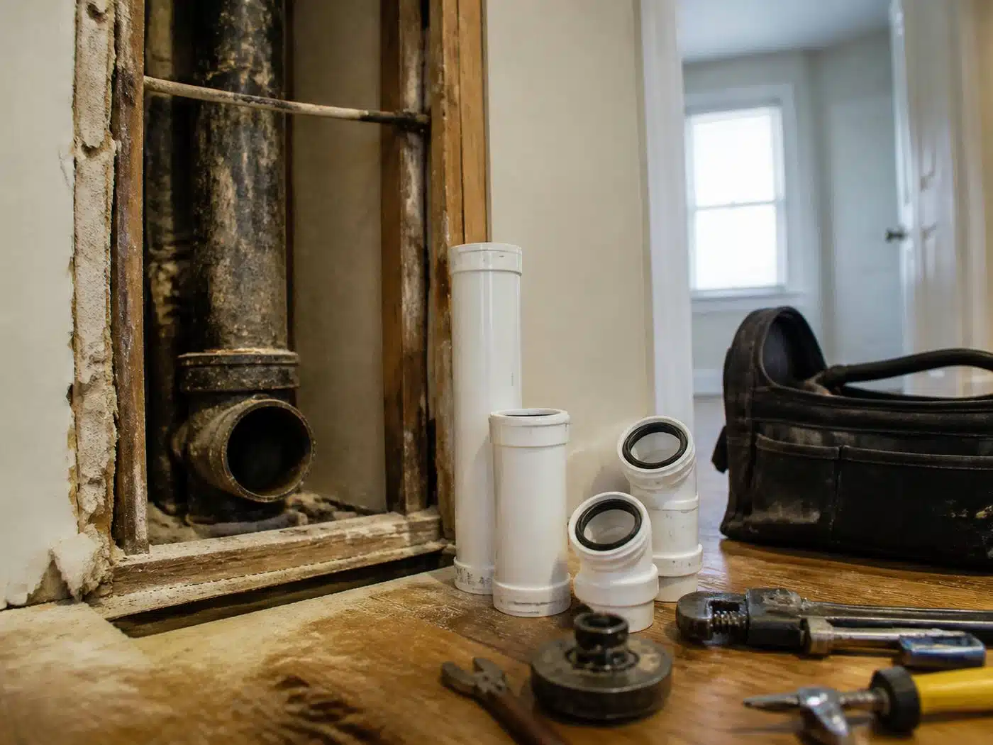 Wider view of the work area, scaled cast iron soil stack cut away with new PVC sections staged in a Denver home