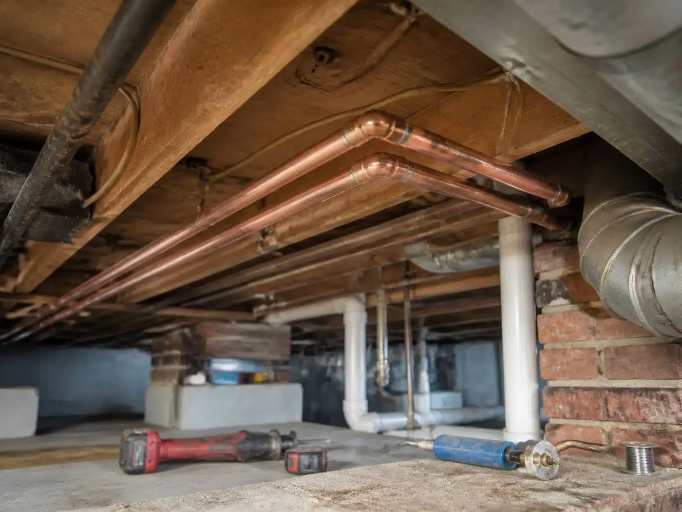 Wider view of the work area, new copper water lines with soldered elbows running along joists in a Denver basement