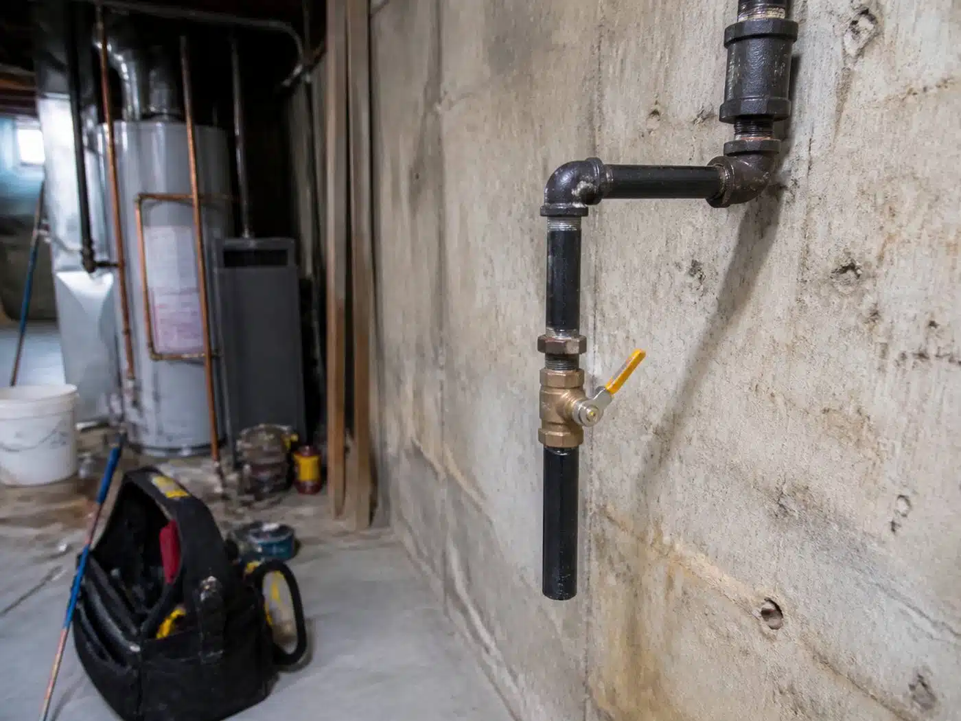 Wider view of the work area, new black iron gas piping with a drip leg and shutoff valve run through a Denver basement
