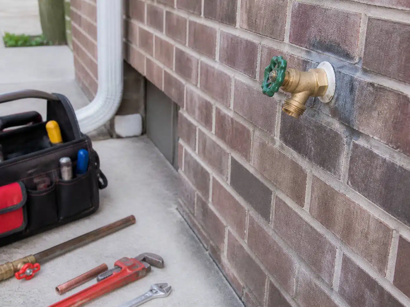 Wider view of the work area, new frost-free hose bib installed through the brick exterior wall of a Denver home