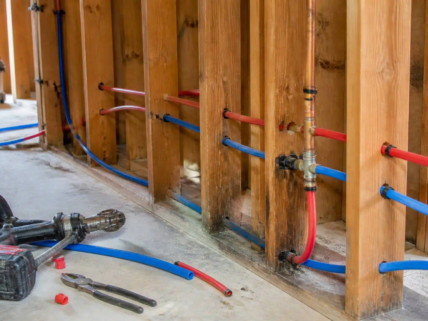 Wider view of the work area, red and blue PEX tubing run through basement floor joists during a Denver repipe