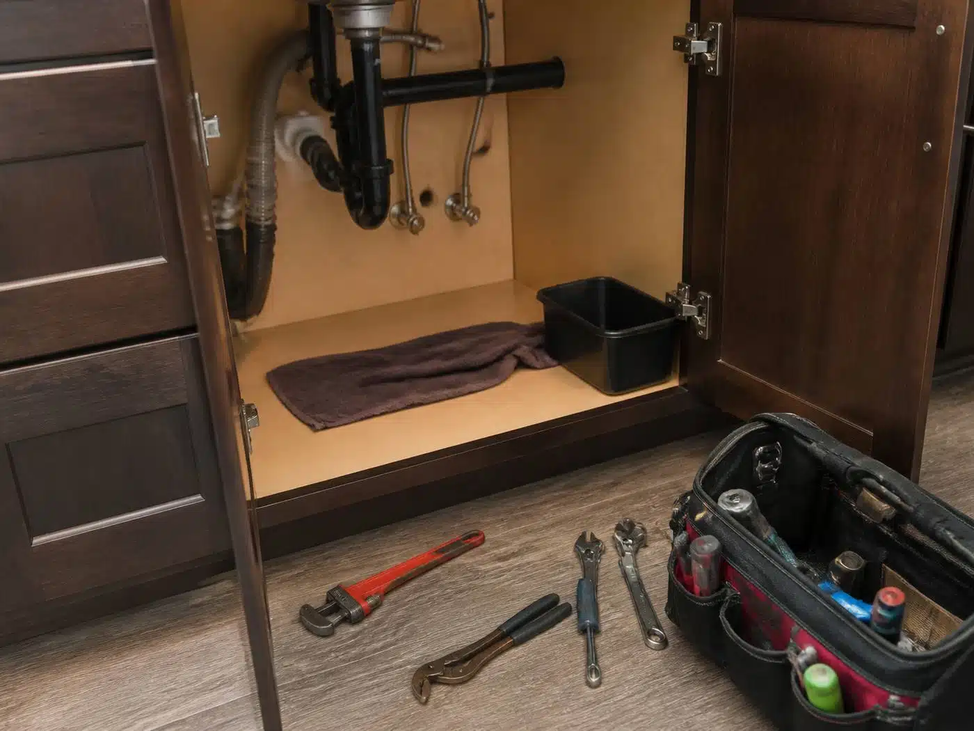 Wider view of the work area, plumbing repair underway beneath a sink in a Denver home