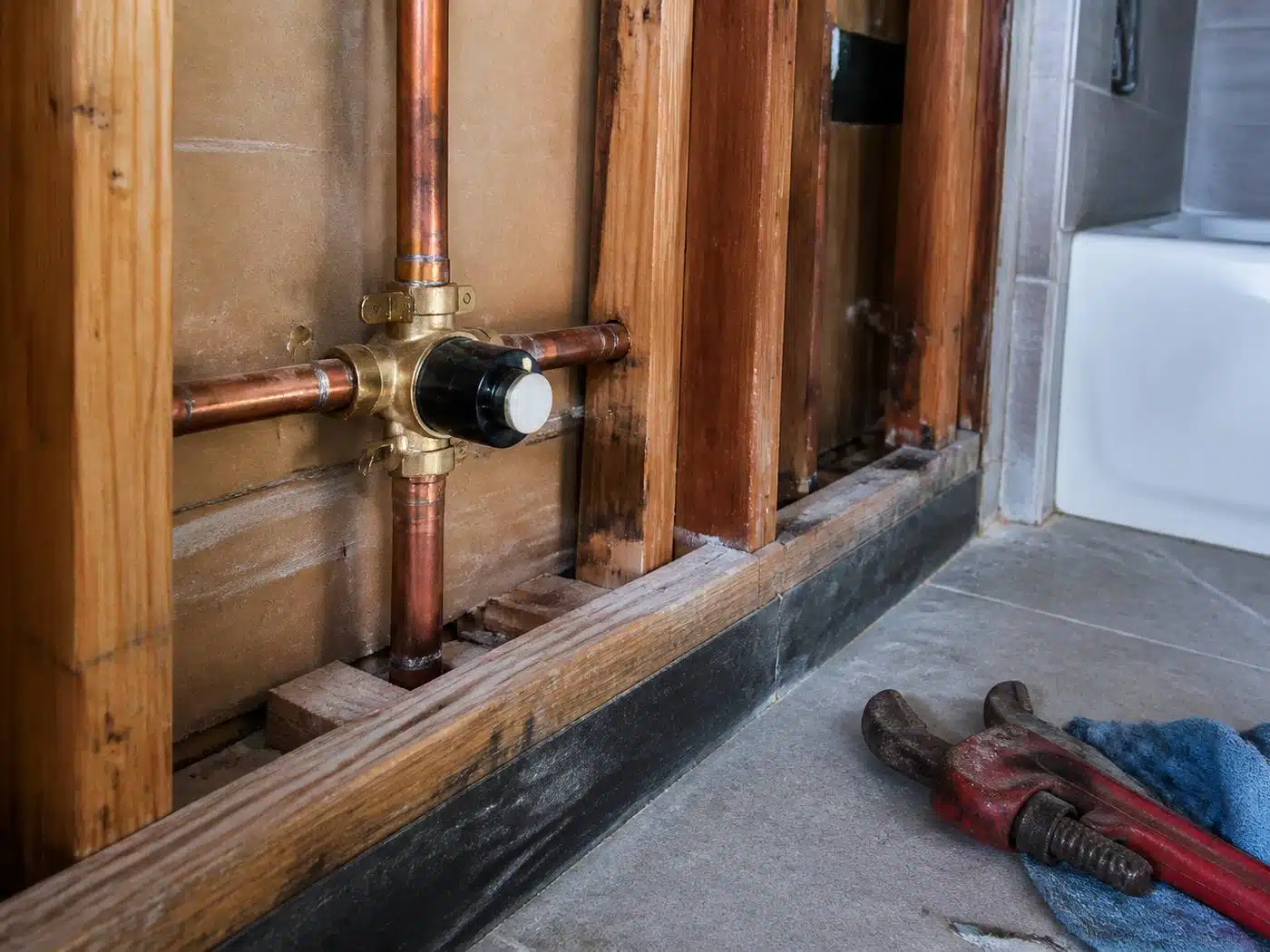 Wider view of the work area, pressure balance shower valve soldered into copper stub-outs behind an open Denver shower wall